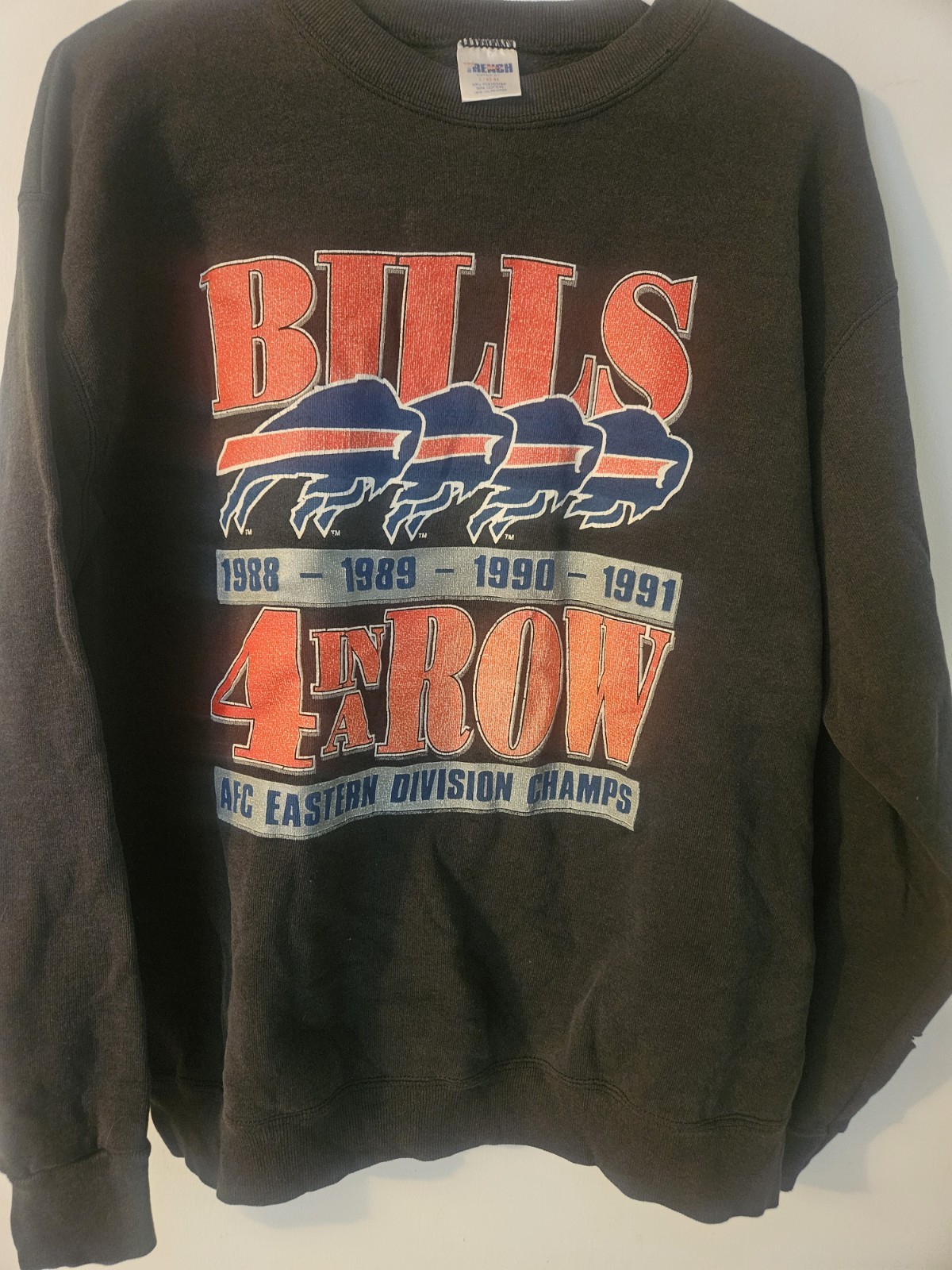 This vintage 1991 NFL Trench brand sweatshirt features a “Bills 4 in a Row”…
